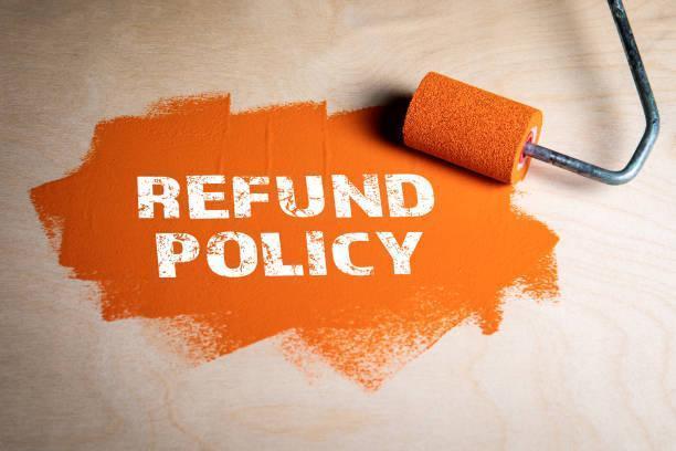 Refund Policy concept. Paint roller with orange paint on a wooden surface.